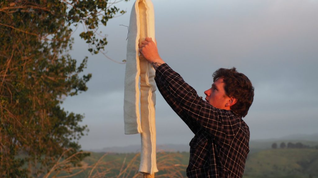 Person installing protective wool cover on a pole.